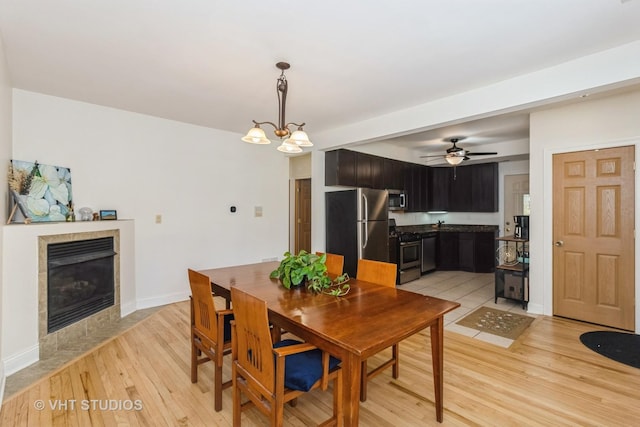 5416 W Windsor Ave Unit 1N, Chicago, IL 60630 - dining space with light wood-style floors, a fireplace, a chandelier, and a ceiling fan