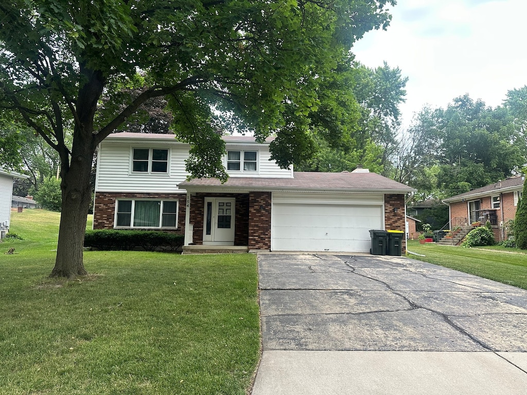 154 Howard Ave, East Dundee, IL 60118 - view of front of house with brick siding, a garage, asphalt driveway, and a front lawn
