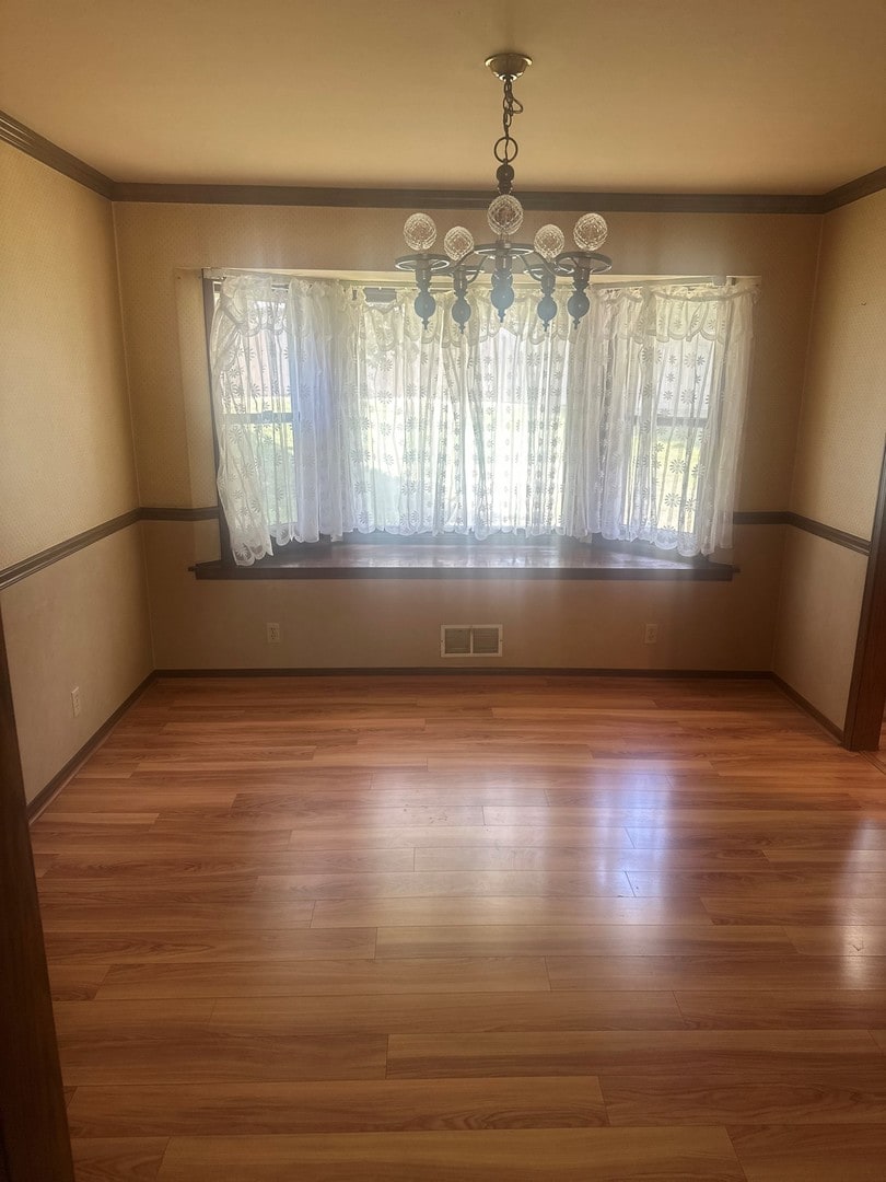 154 Howard Ave, East Dundee, IL 60118 - unfurnished dining area with a chandelier, wood finished floors, and crown molding