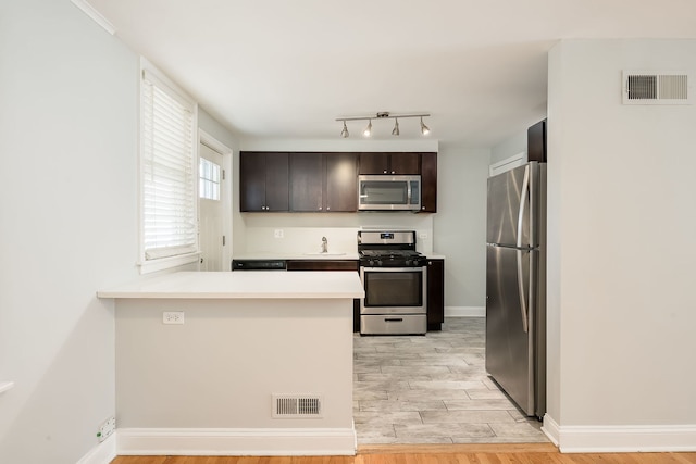 5641 W Carmen Ave, Chicago, IL 60630 - kitchen with stainless steel appliances, light countertops, dark brown cabinetry, and a peninsula