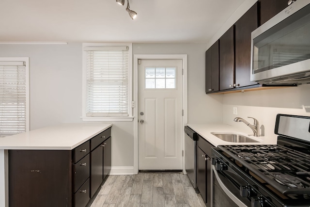 5641 W Carmen Ave, Chicago, IL 60630 - kitchen featuring appliances with stainless steel finishes, light countertops, a peninsula, dark brown cabinets, and light wood-style floors