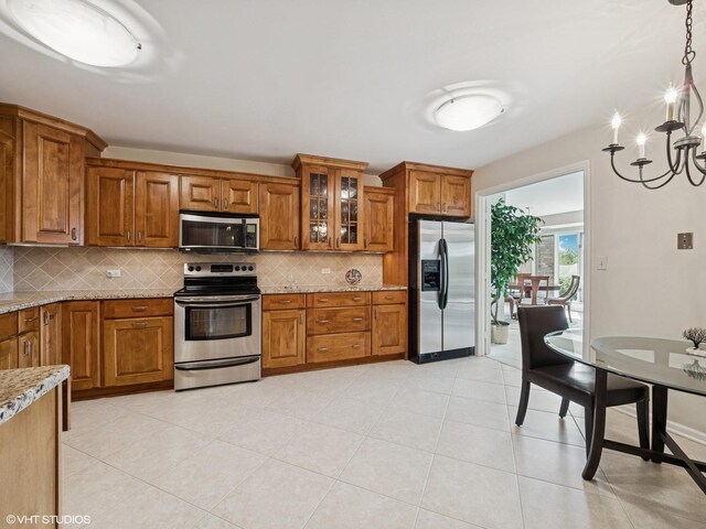 1671 Mission Hills Rd Unit 308, Northbrook, IL 60062 - kitchen with stainless steel appliances, brown cabinets, backsplash, and light stone countertops