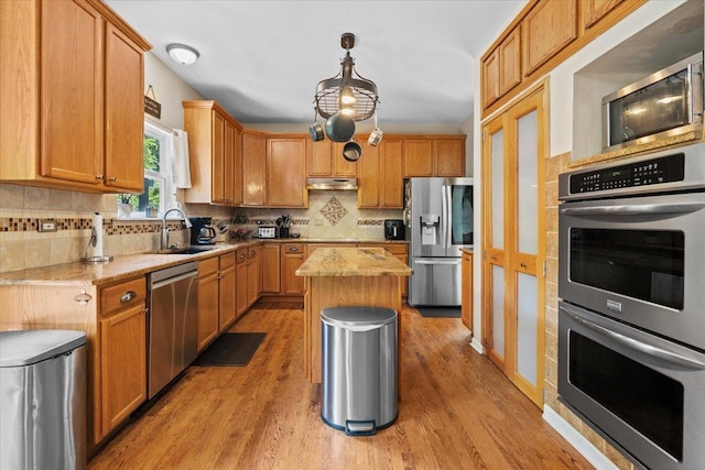33 Sarah Dr, Crystal Lake, IL 60014 - kitchen featuring appliances with stainless steel finishes, tasteful backsplash, under cabinet range hood, a kitchen island, and light wood-style flooring