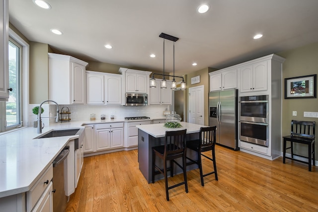 520 Meadowwood Ln, Oswego, IL 60543 - kitchen with appliances with stainless steel finishes, a breakfast bar, white cabinets, a center island, and recessed lighting