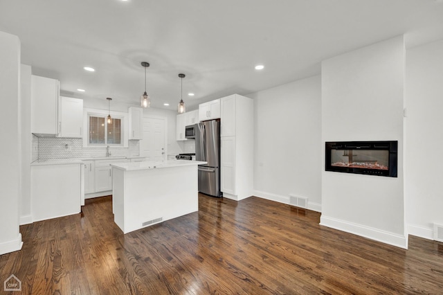 8559 S Drexel Ave, Chicago, IL 60619 - kitchen featuring stainless steel appliances, white cabinetry, a glass covered fireplace, backsplash, and recessed lighting