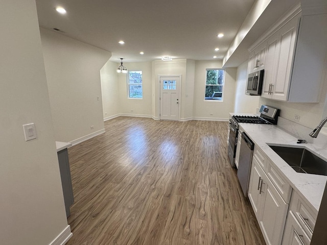 1325 S 50th Ct, Cicero, IL 60804 - kitchen featuring appliances with stainless steel finishes, wood finished floors, light stone countertops, recessed lighting, and white cabinetry