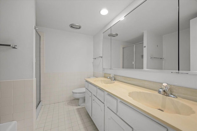 650 Winnetka Mews Unit 311, Winnetka, IL 60093 - bathroom with double vanity, tile patterned floors, a stall shower, a wainscoted wall, and tile walls