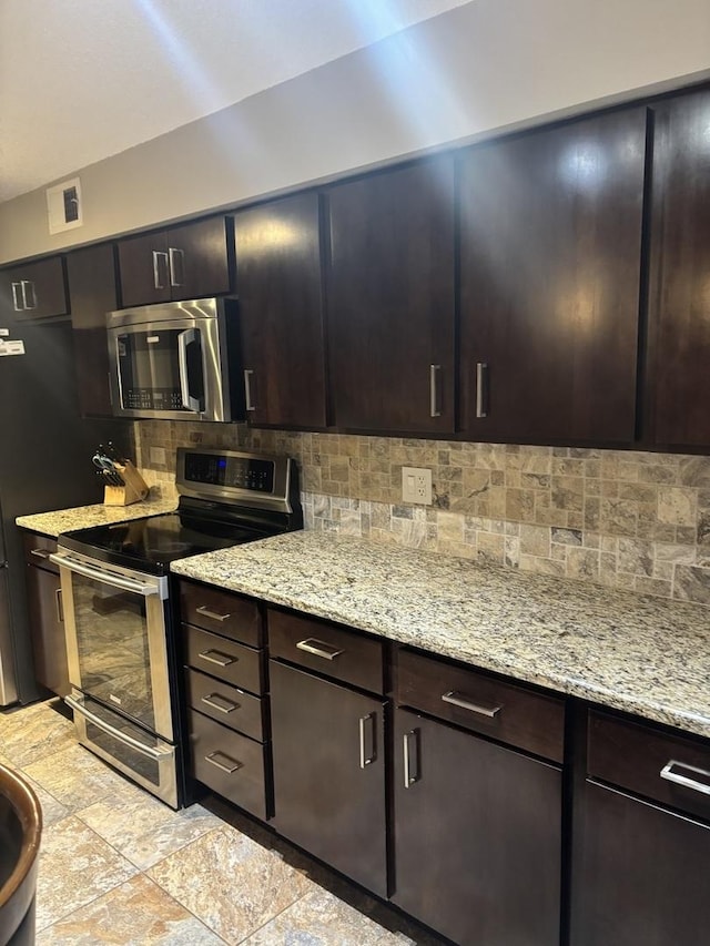 1017 Buccaneer Dr Unit 5, Schaumburg, IL 60173 - kitchen featuring stainless steel appliances, backsplash, light stone countertops, light stone finish floors, and dark brown cabinetry