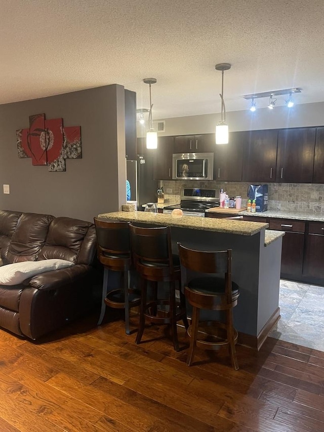 1017 Buccaneer Dr Unit 5, Schaumburg, IL 60173 - kitchen with appliances with stainless steel finishes, a breakfast bar area, light stone counters, tasteful backsplash, and open floor plan