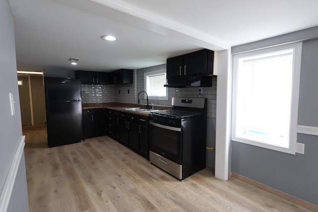15239 Vincennes Rd, Phoenix, IL 60426 - kitchen with gas stove, freestanding refrigerator, under cabinet range hood, dark cabinetry, and backsplash