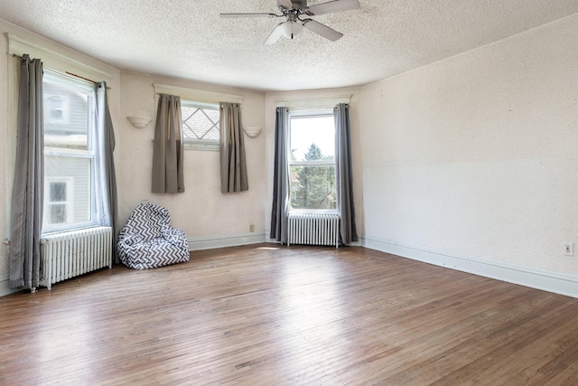 818 N State St, Belvidere, IL 61008 - spare room featuring radiator, a ceiling fan, wood finished floors, a textured ceiling, and a textured wall