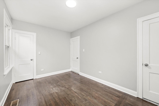 unfurnished bedroom with baseboards and dark wood finished floors