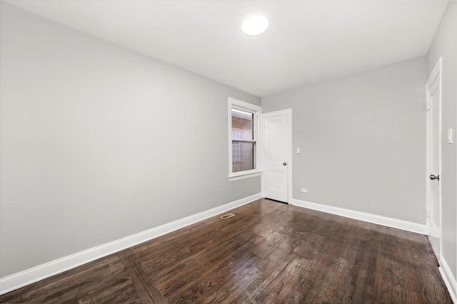 spare room featuring dark wood-style floors and baseboards