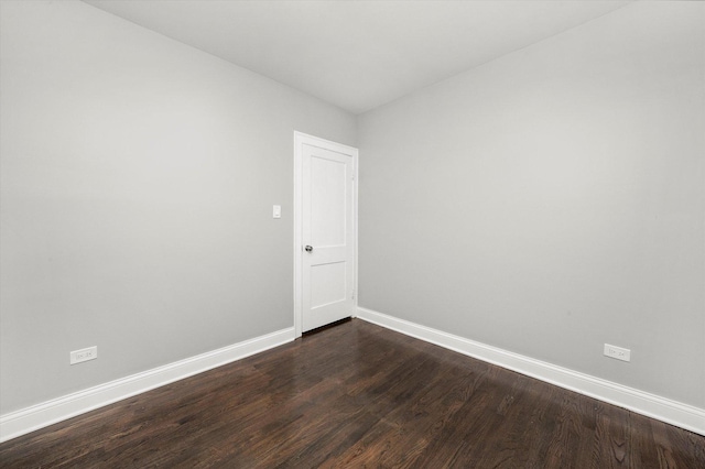 empty room featuring baseboards and dark wood finished floors