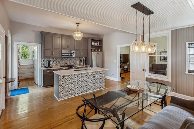 1422 Wesley Ave, Evanston, IL 60201 - kitchen featuring appliances with stainless steel finishes, light countertops, light wood-style flooring, and a center island with sink
