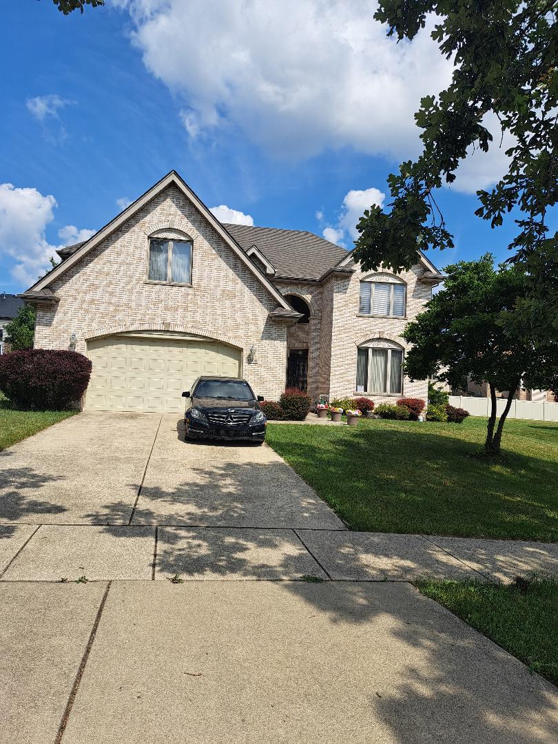 3806 Carrington Dr, Hazel Crest, IL 60429 - french country style house featuring driveway, a front lawn, an attached garage, and brick siding