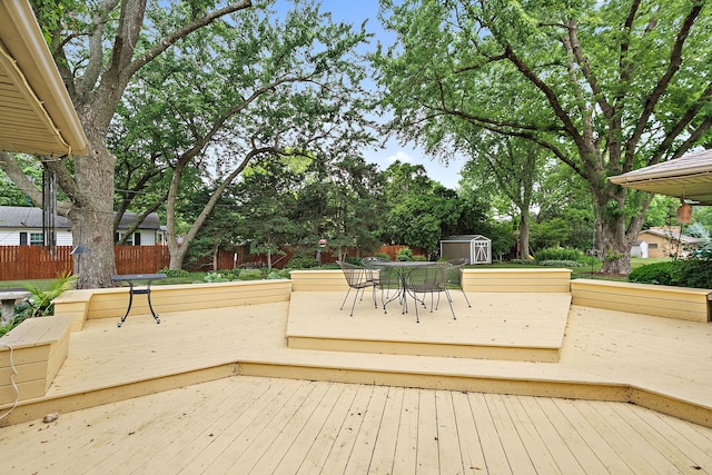 306 Wing Park Blvd, Elgin, IL 60123 - wooden terrace with a storage shed, outdoor dining area, and view of wooded area