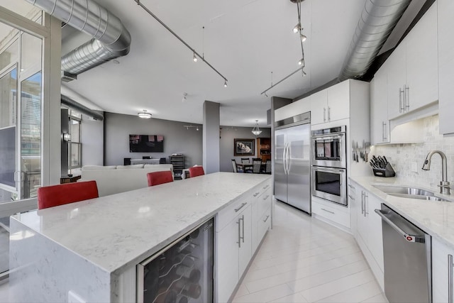 1001 W Madison St Unit 710, Chicago, IL 60607 - kitchen featuring appliances with stainless steel finishes, wine cooler, open floor plan, decorative backsplash, and white cabinets