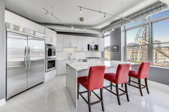1001 W Madison St Unit 710, Chicago, IL 60607 - kitchen featuring appliances with stainless steel finishes, decorative backsplash, plenty of natural light, and white cabinetry