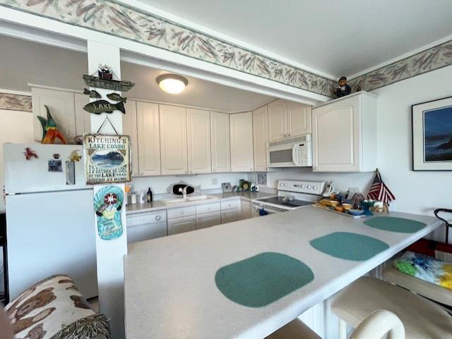 56 Vail Colony Unit 1, Fox Lake, IL 60020 - kitchen with white appliances, light countertops, a breakfast bar, and white cabinets