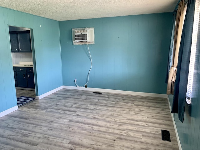 3122 Arlington Dr, Princeton, IL 61356 - unfurnished room featuring wood finished floors, a wall mounted AC, and a textured ceiling
