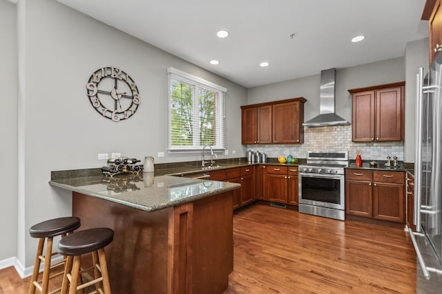 10 Park Ave, River Forest, IL 60305 - kitchen with wall chimney exhaust hood, stainless steel appliances, a peninsula, dark stone counters, and wood finished floors