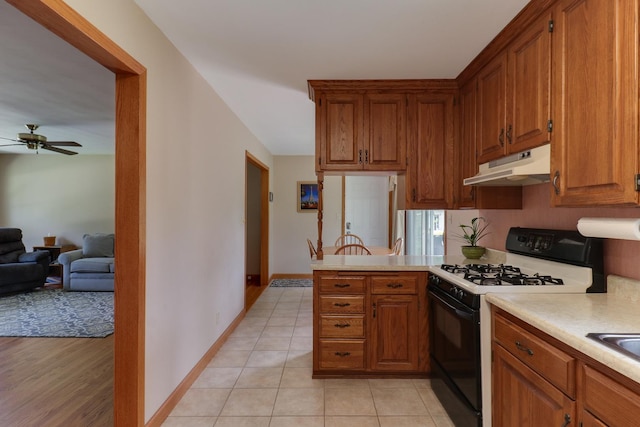 1001 Sheridan Rd, Normal, IL 61761 - kitchen with black gas stove, under cabinet range hood, light countertops, ceiling fan, and brown cabinets