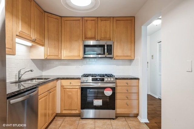 1220 Park Ave W Unit 110, Highland Park, IL 60035 - kitchen with stainless steel appliances, dark stone counters, tasteful backsplash, and light tile patterned floors