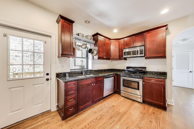 3253 W Palmer St Unit 301, Chicago, IL 60647 - kitchen featuring appliances with stainless steel finishes, light wood-type flooring, dark brown cabinets, arched walkways, and dark stone counters