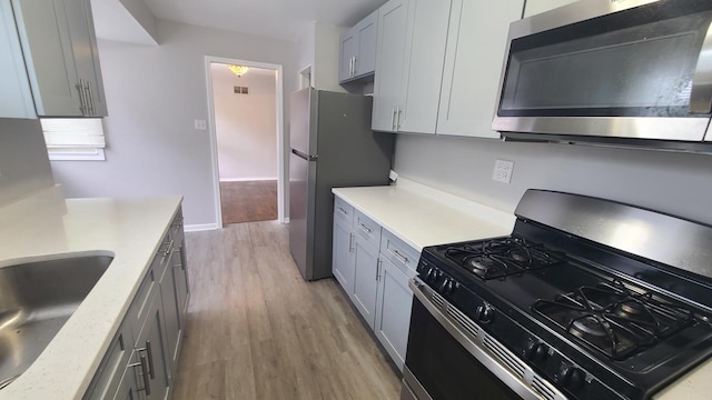 16002 Spaulding Ave, Markham, IL 60428 - kitchen with appliances with stainless steel finishes, light wood-style floors, light countertops, and gray cabinetry