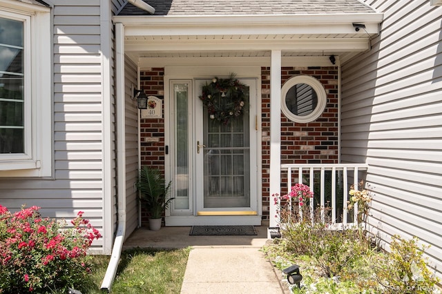 40 Jackson Ln, Streamwood, IL 60107 - view of exterior entry with brick siding, a porch, and roof with shingles
