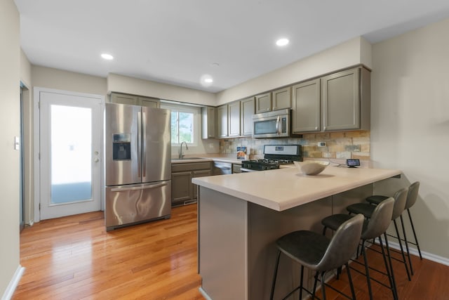 231 E Fullerton Ave, Glendale Heights, IL 60139 - kitchen with stainless steel appliances, gray cabinets, a peninsula, a breakfast bar, and light countertops