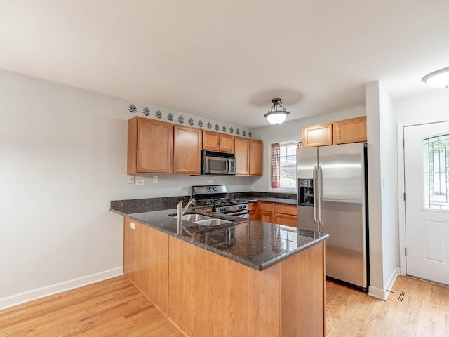 525 W Washington Ave Unit 9, Lake Bluff, IL 60044 - kitchen featuring stainless steel appliances, a peninsula, light wood-style flooring, dark stone countertops, and brown cabinets