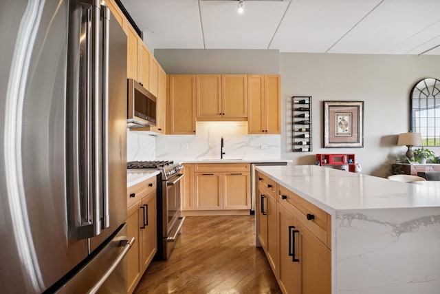 3125 W Fullerton Ave Unit 508, Chicago, IL 60647 - kitchen featuring appliances with stainless steel finishes, light brown cabinetry, wood finished floors, tasteful backsplash, and a center island