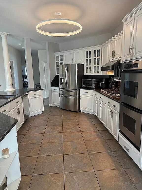 06N274 W Ridgewood Ln, Saint Charles, IL 60175 - kitchen featuring appliances with stainless steel finishes, dark tile patterned flooring, dark countertops, and white cabinetry