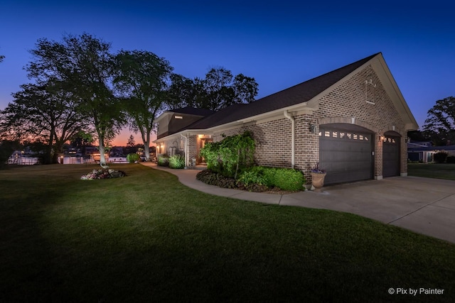 1913 N Woodlawn Park Ave, Mchenry, IL 60051 - property exterior at dusk with brick siding, a lawn, driveway, and an attached garage