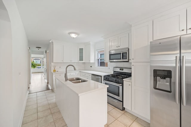 7004 W School St, Chicago, IL 60634 - kitchen featuring appliances with stainless steel finishes, backsplash, white cabinetry, an island with sink, and light tile patterned flooring