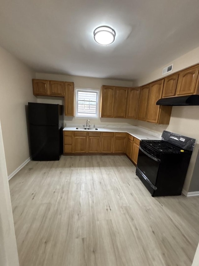 6638 S Albany Ave, Chicago, IL 60629 - kitchen with black appliances, under cabinet range hood, light wood-style flooring, light countertops, and brown cabinets