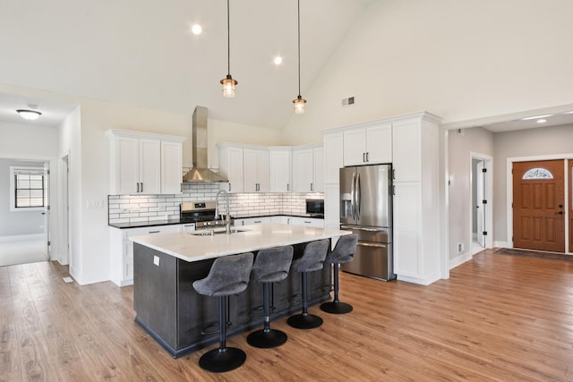220 S Primrose Dr, Coal City, IL 60416 - kitchen featuring stainless steel appliances, wall chimney range hood, tasteful backsplash, white cabinetry, and high vaulted ceiling
