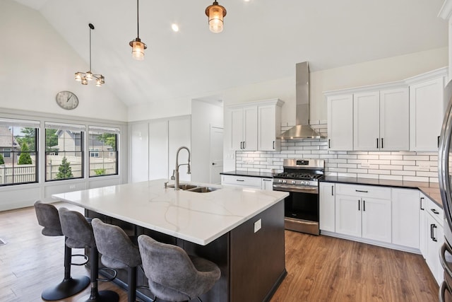 220 S Primrose Dr, Coal City, IL 60416 - kitchen with stainless steel gas stove, wall chimney range hood, backsplash, a center island with sink, and wood finished floors