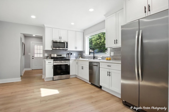 312 Country Club Dr, Mchenry, IL 60050 - kitchen with stainless steel appliances, decorative backsplash, light countertops, light wood-type flooring, and white cabinets
