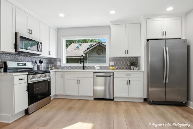 312 Country Club Dr, Mchenry, IL 60050 - kitchen featuring stainless steel appliances, white cabinetry, tasteful backsplash, light wood-style flooring, and light countertops