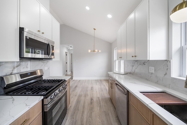 8858 S Calumet Ave, Chicago, IL 60619 - kitchen featuring appliances with stainless steel finishes, a chandelier, light wood-type flooring, light stone countertops, and pendant lighting