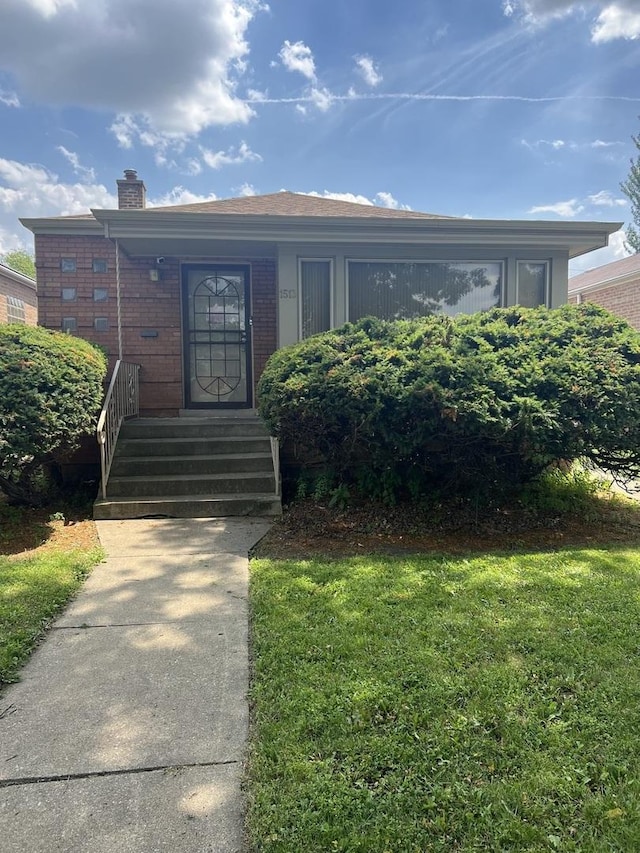 1513 E 86th Pl, Chicago, IL 60619 - view of front facade with a chimney, brick siding, and a front lawn