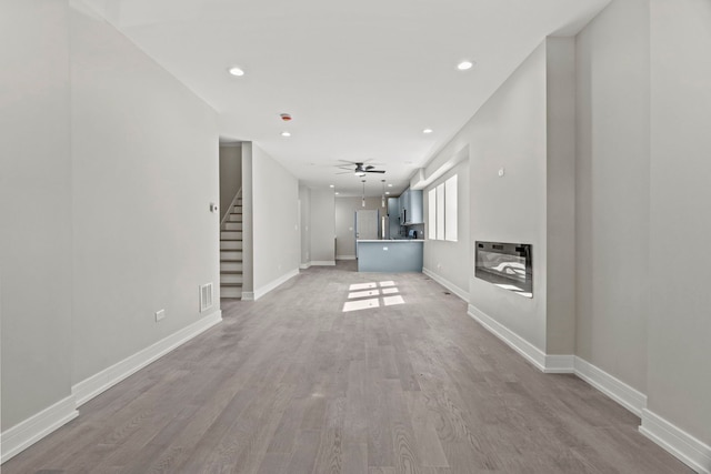 7711 S Ridgeland Ave, Chicago, IL 60649 - unfurnished living room with stairs, light wood-style floors, recessed lighting, and ceiling fan