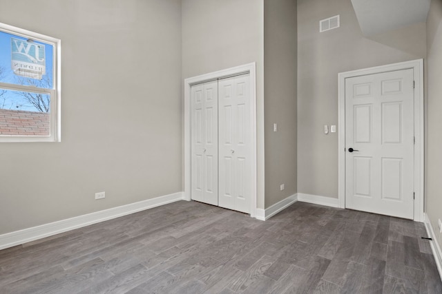 7711 S Ridgeland Ave, Chicago, IL 60649 - unfurnished bedroom with dark wood-type flooring, a towering ceiling, and a closet