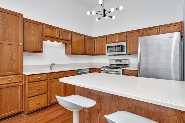 16636 Winding Creek Rd, Plainfield, IL 60586 - kitchen with appliances with stainless steel finishes, light countertops, brown cabinetry, a towering ceiling, and a chandelier