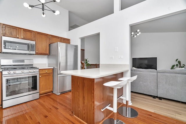 16636 Winding Creek Rd, Plainfield, IL 60586 - kitchen featuring appliances with stainless steel finishes, a chandelier, a kitchen breakfast bar, light countertops, and light wood finished floors