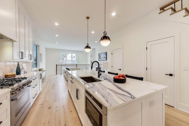 2611 W Carmen Ave, Chicago, IL 60625 - kitchen featuring stainless steel appliances, light wood finished floors, an island with sink, white cabinetry, and recessed lighting