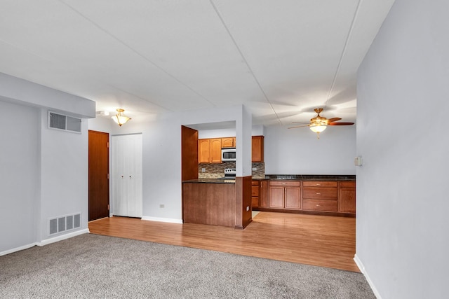 814 N River Rd Unit 1D, Mount Prospect, IL 60056 - kitchen featuring appliances with stainless steel finishes, brown cabinets, light carpet, dark countertops, and tasteful backsplash